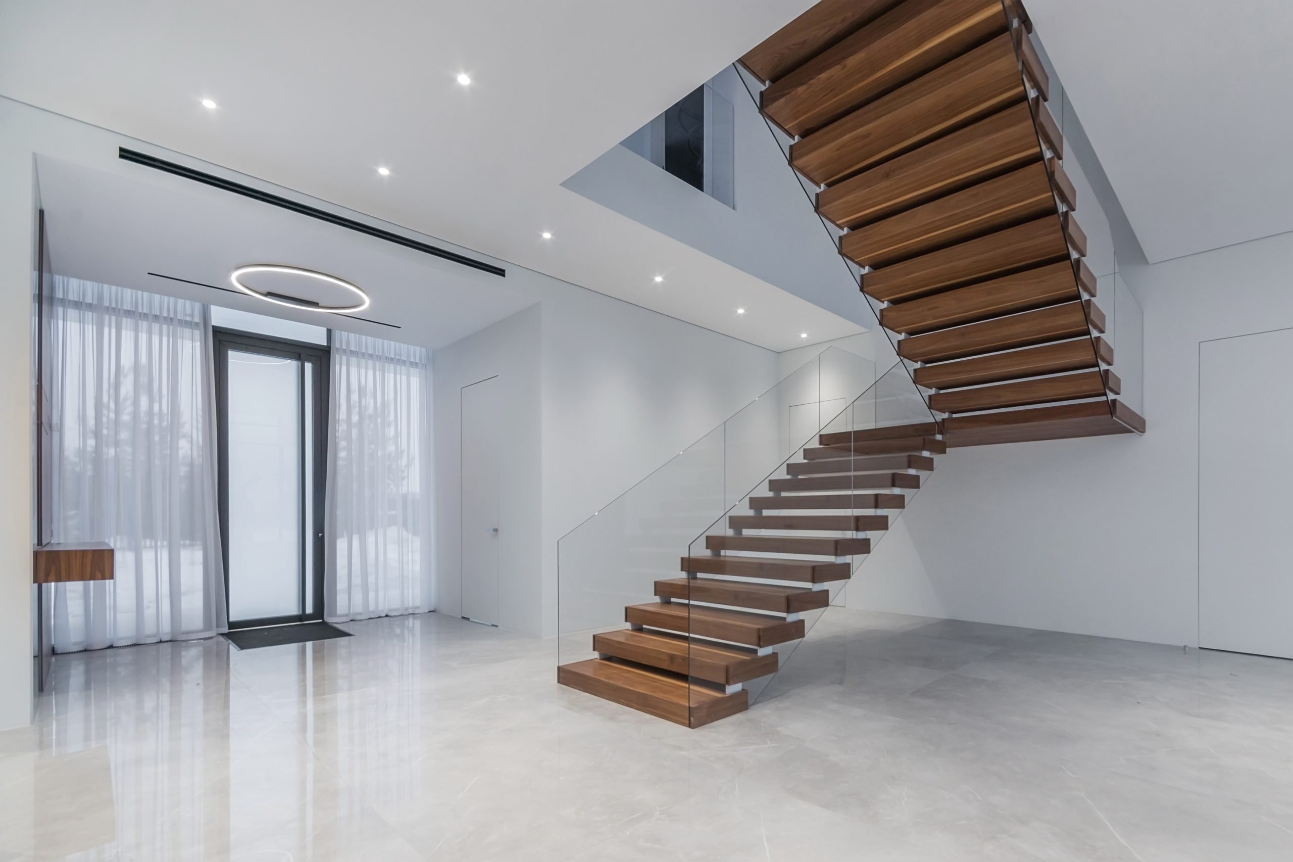 elegance and style in the interior of a country house. glass entrance door, stairs with wooden steps and glass railings.