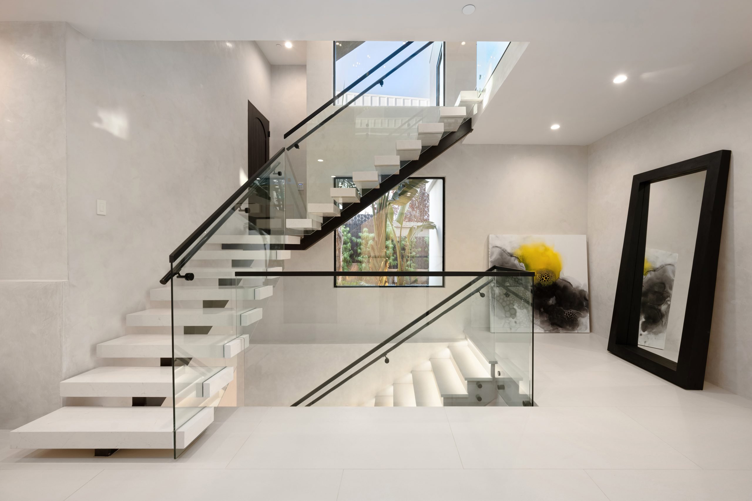 modern home interior featuring a set of stairs with white carpeting and glass railings
